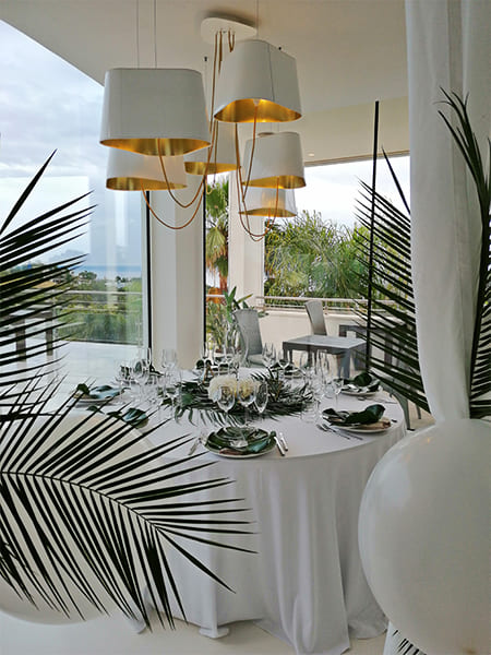 Mesa decorada con cubiertos, servilletas verdes y lámparas doradas en la terraza del hotel de lujo en Mallorca