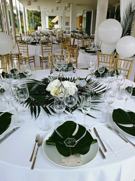 Hojas de palmera sobre los platos de una mesa blanca y bien decorada