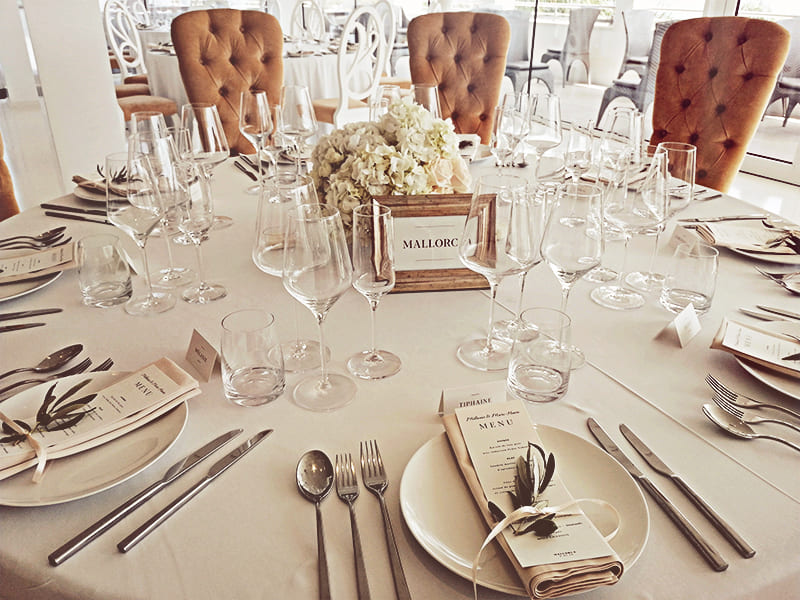 Mesa decorada con cubiertos, vasos de vino y ramos de flores