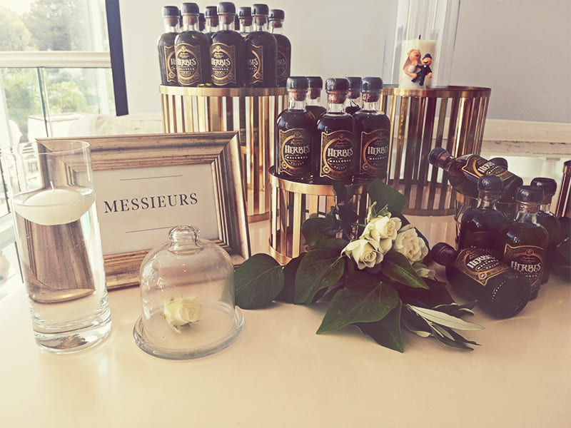 Pequeñas botellas de hierbas y balsámico en una mesa decorada con velas