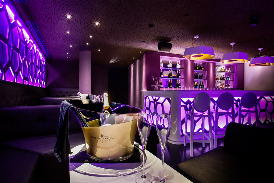 El bar oscuro del hotel en Mallorca con un cubo de champán y luces lila