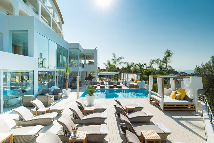 Un día de sol en el hotel de lujo en Mallorca con una piscina, tumbonas y palmeras