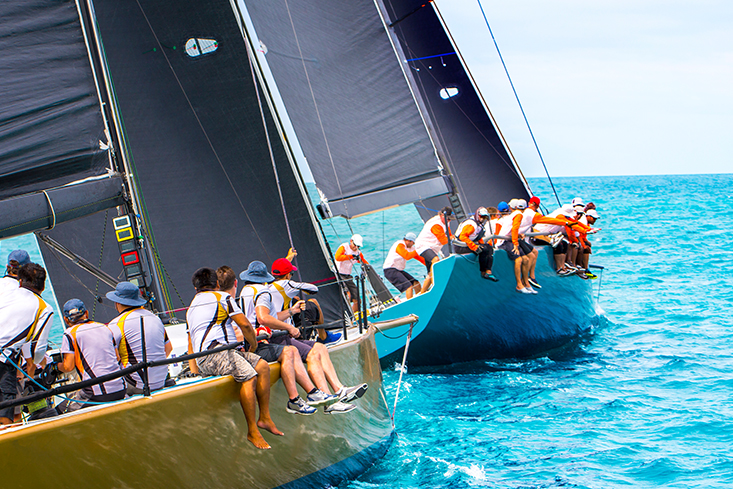 Several people sit with life jackets on two sailing boats going for a ride