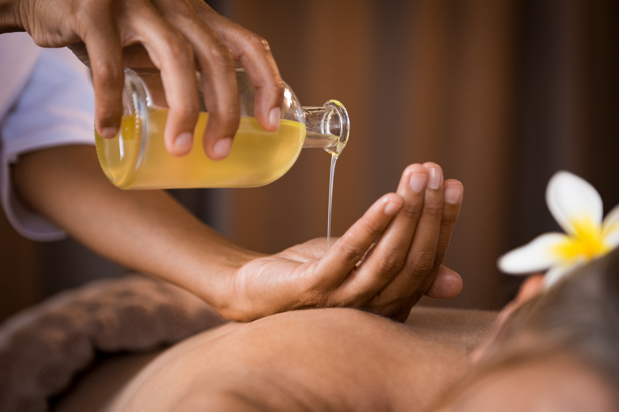 The massage oil is poured from a bottle into the hand.
